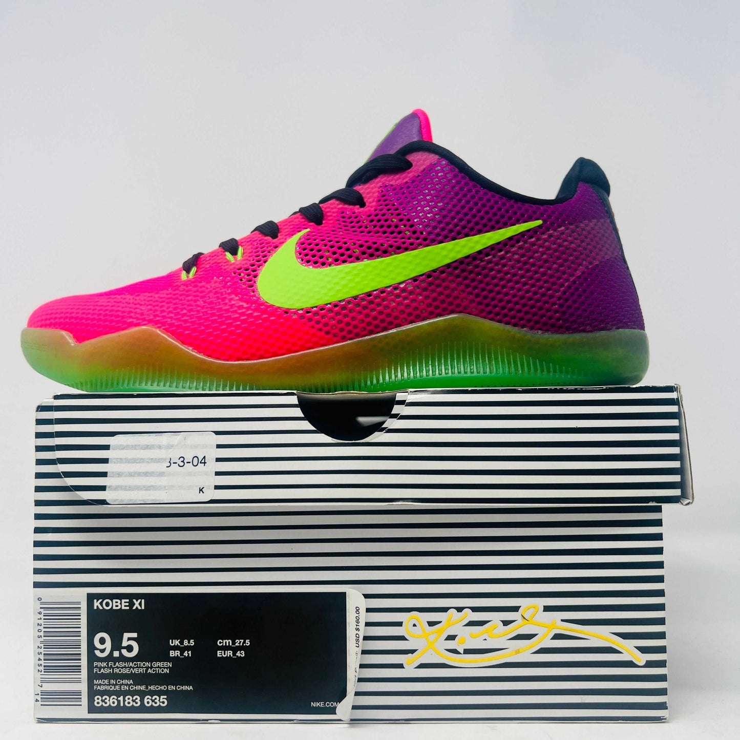 Nike Kobe 11 EM Low Mambacurial sneakers in size 9.5, vibrant pink and green colorway, slightly worn, displayed on striped box.