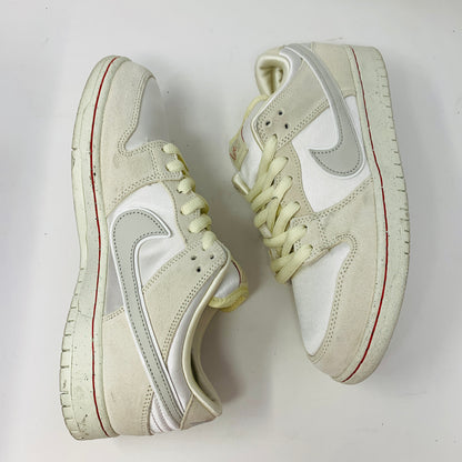 The Nike SB Dunk Low City of Love Light Bone sneakers feature a white base with light gray swoosh designs, red accents on the soles, and slightly off-white laces, creating a subtle color scheme against the white background.