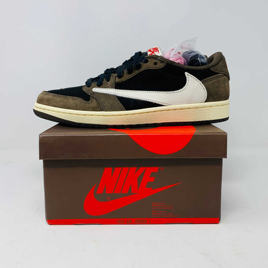 A pair of BRAND NEW Jordan 1 Low OG Travis Scott Mocha sneakers in black and brown, featuring a white swoosh, displayed on a brown shoe box with a red logo. 100% Authentic with EXTRA LACES partially visible inside.