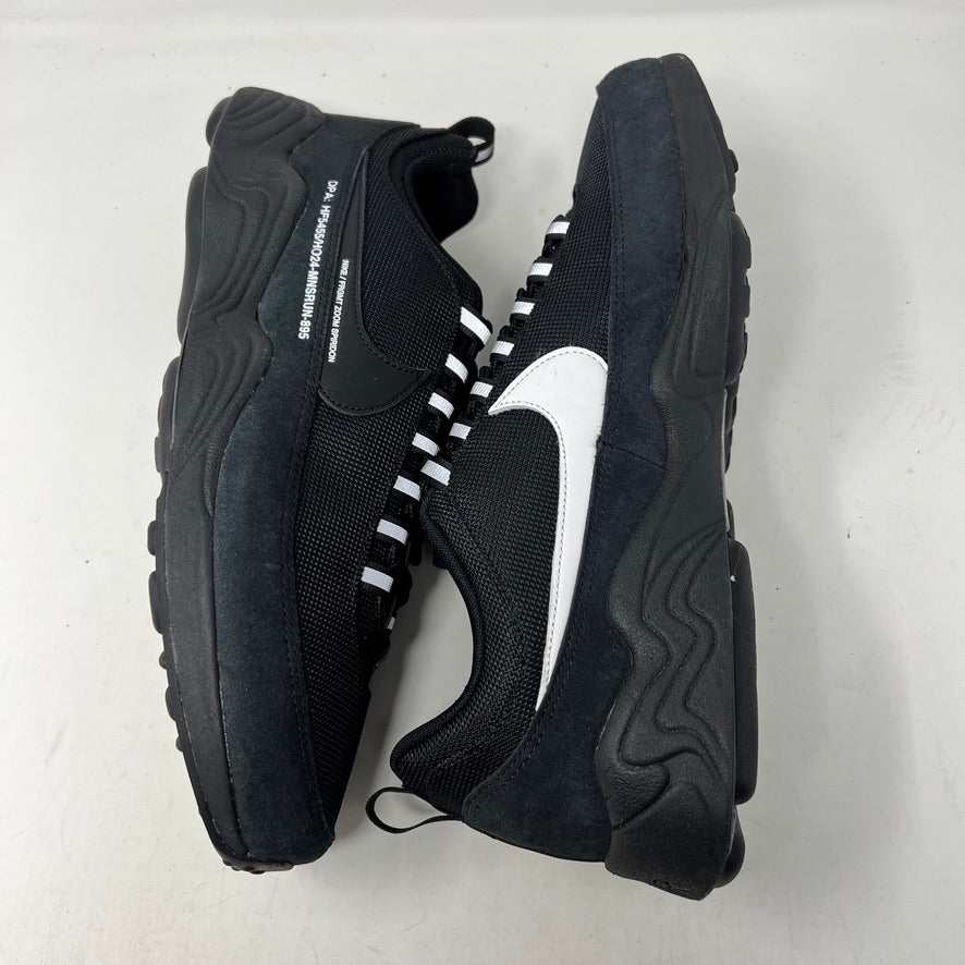 The Nike Air Zoom Spiridon Fragment Design Black, an authentic athletic shoe with a textured design and subtle branding, is displayed on a blue shoebox with a lightning bolt logo. It features white text indicating the product code against a plain white background.