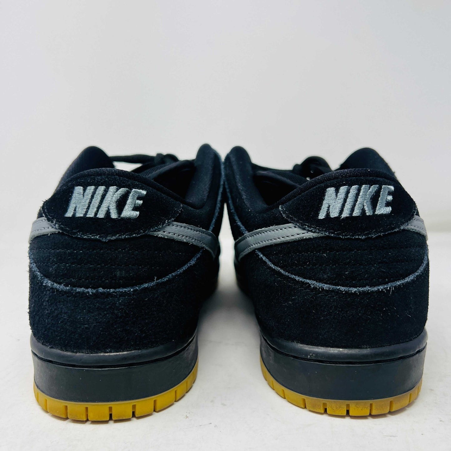 A pair of authentic Nike SB Dunk Low Fog sneakers in black with gray swoosh logos and vibrant yellow soles, accompanied by extra laces, displayed on a pristine white background from Holy Ground Sneaker Shop.