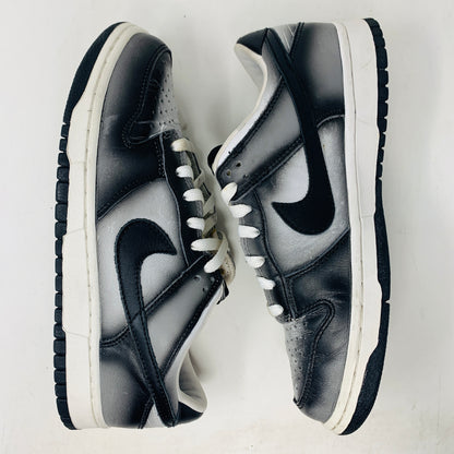 The Nike Dunk Low Haze 2003 sneakers are displayed from the side, featuring white laces and a black swoosh logo. They have a worn appearance against a white surface.